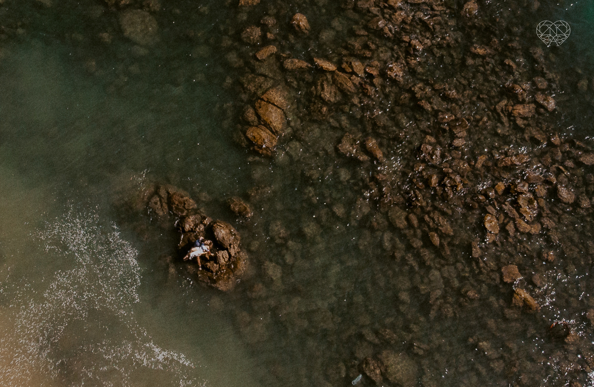ensaio pre casamento pre wedding na praia das conchas no guaruja noiva de roupa branca e buque e noivo com roupa sociall fotos feitas na agua  na grama e correndo nas pedras ensaio feito pela fotografa premiada nayara andrade de santos
