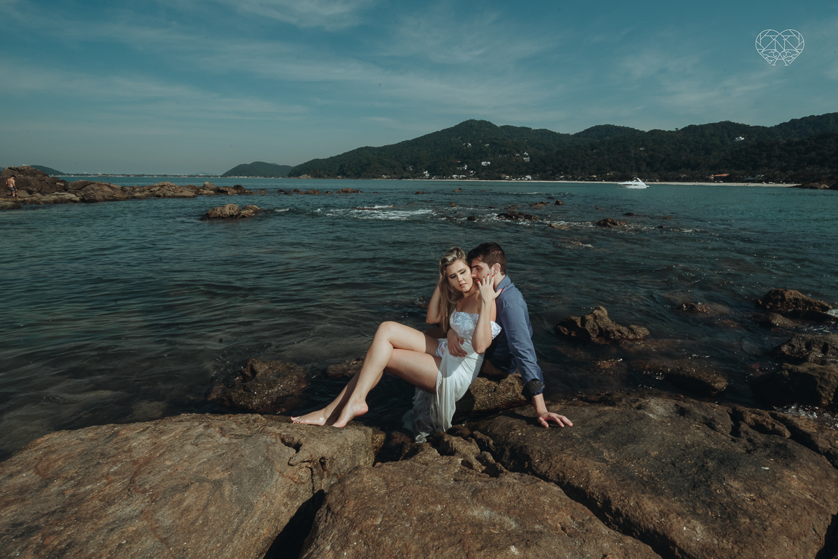ensaio pre casamento pre wedding na praia das conchas no guaruja noiva de roupa branca e buque e noivo com roupa sociall fotos feitas na agua  na grama e correndo nas pedras ensaio feito pela fotografa premiada nayara andrade de santos
