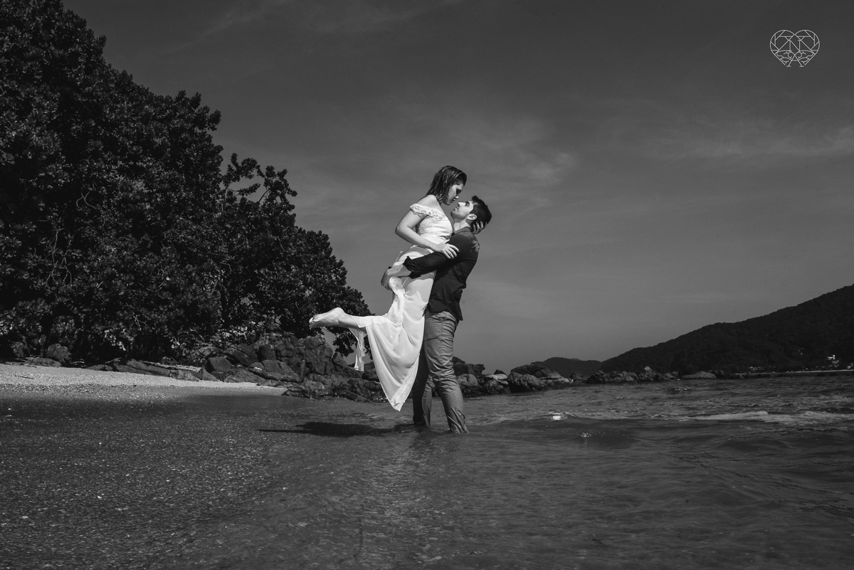 ensaio pre casamento pre wedding na praia das conchas no guaruja noiva de roupa branca e buque e noivo com roupa sociall fotos feitas na agua  na grama e correndo nas pedras ensaio feito pela fotografa premiada nayara andrade de santos