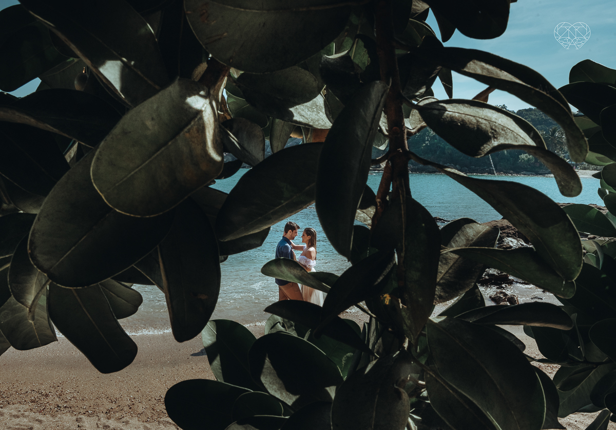 ensaio pre casamento pre wedding na praia das conchas no guaruja noiva de roupa branca e buque e noivo com roupa sociall fotos feitas na agua  na grama e correndo nas pedras ensaio feito pela fotografa premiada nayara andrade de santos
