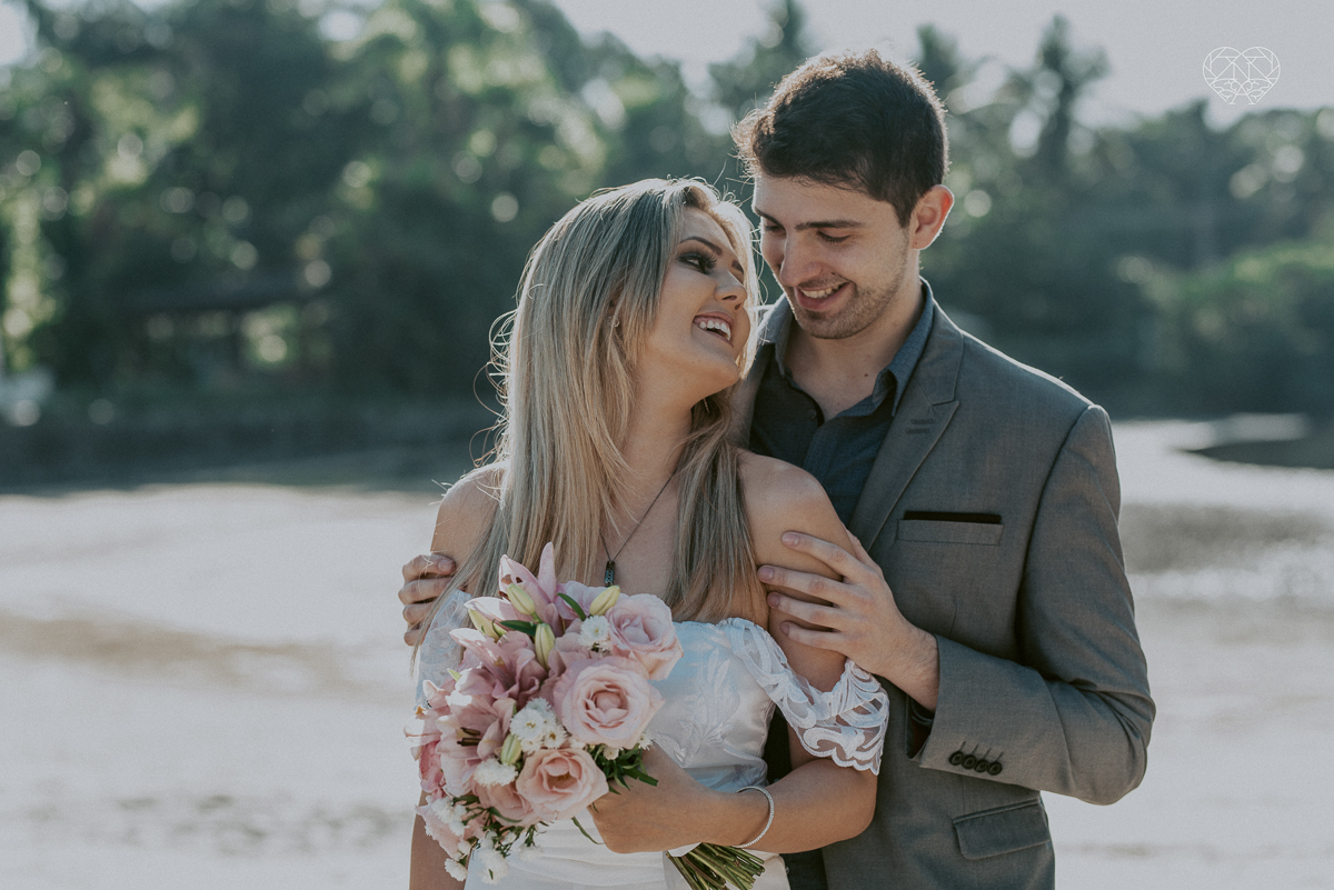 ensaio pre casamento pre wedding na praia das conchas no guaruja noiva de roupa branca e buque e noivo com roupa sociall fotos feitas na agua  na grama e correndo nas pedras ensaio feito pela fotografa premiada nayara andrade de santos