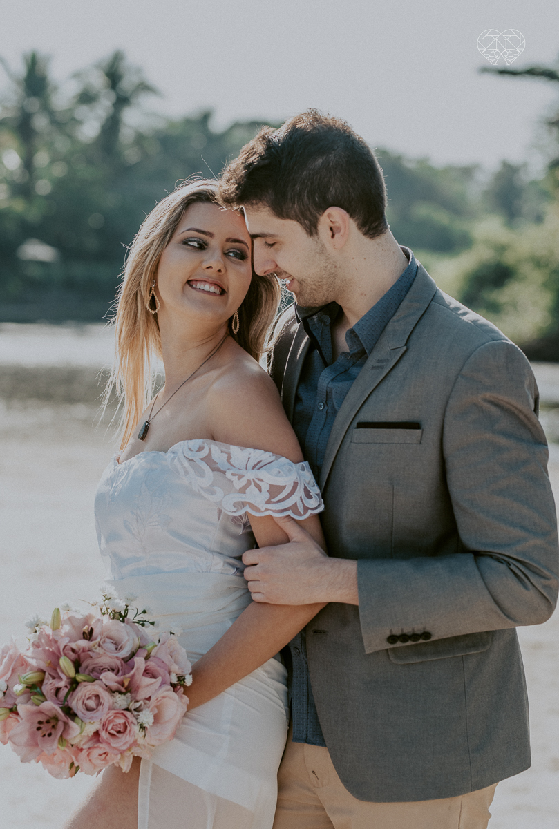 ensaio pre casamento pre wedding na praia das conchas no guaruja noiva de roupa branca e buque e noivo com roupa sociall fotos feitas na agua  na grama e correndo nas pedras ensaio feito pela fotografa premiada nayara andrade de santos