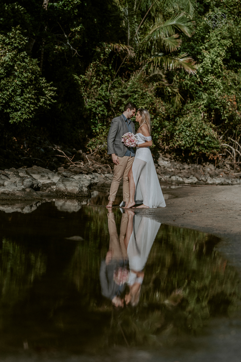ensaio pre casamento pre wedding na praia das conchas no guaruja noiva de roupa branca e buque e noivo com roupa sociall fotos feitas na agua  na grama e correndo nas pedras ensaio feito pela fotografa premiada nayara andrade de santos