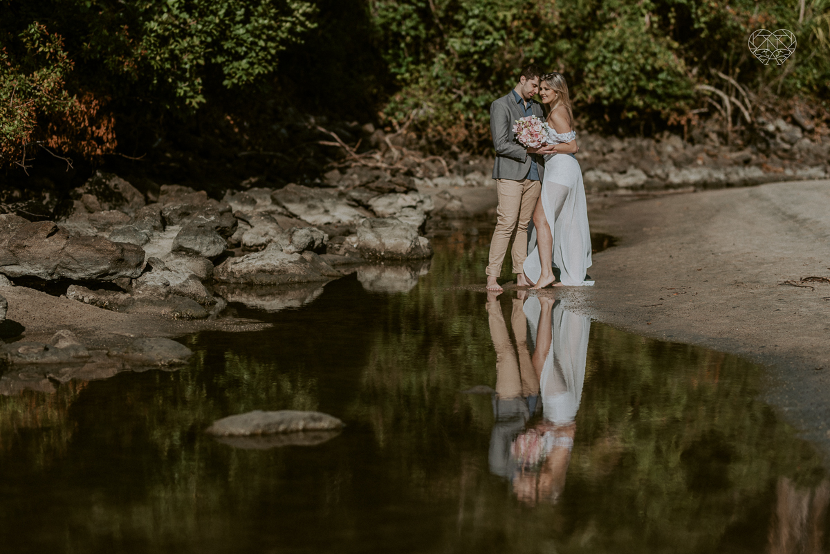 ensaio pre casamento pre wedding na praia das conchas no guaruja noiva de roupa branca e buque e noivo com roupa sociall fotos feitas na agua  na grama e correndo nas pedras ensaio feito pela fotografa premiada nayara andrade de santos