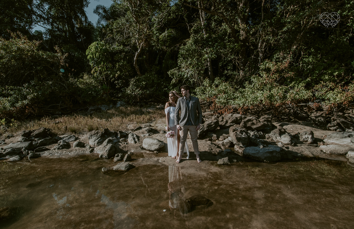 ensaio pre casamento pre wedding na praia das conchas no guaruja noiva de roupa branca e buque e noivo com roupa sociall fotos feitas na agua  na grama e correndo nas pedras ensaio feito pela fotografa premiada nayara andrade de santos