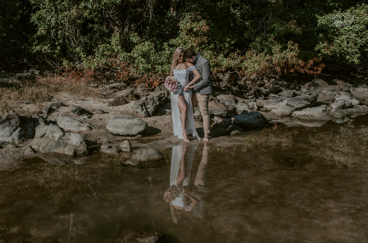 ensaio pre casamento pre wedding na praia das conchas no guaruja noiva de roupa branca e buque e noivo com roupa sociall fotos feitas na agua  na grama e correndo nas pedras ensaio feito pela fotografa premiada nayara andrade de santos