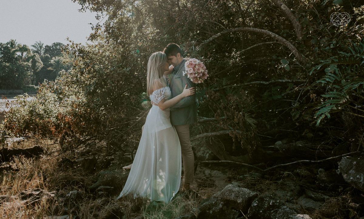 ensaio pre casamento pre wedding na praia das conchas no guaruja noiva de roupa branca e buque e noivo com roupa sociall fotos feitas na agua  na grama e correndo nas pedras ensaio feito pela fotografa premiada nayara andrade de santos