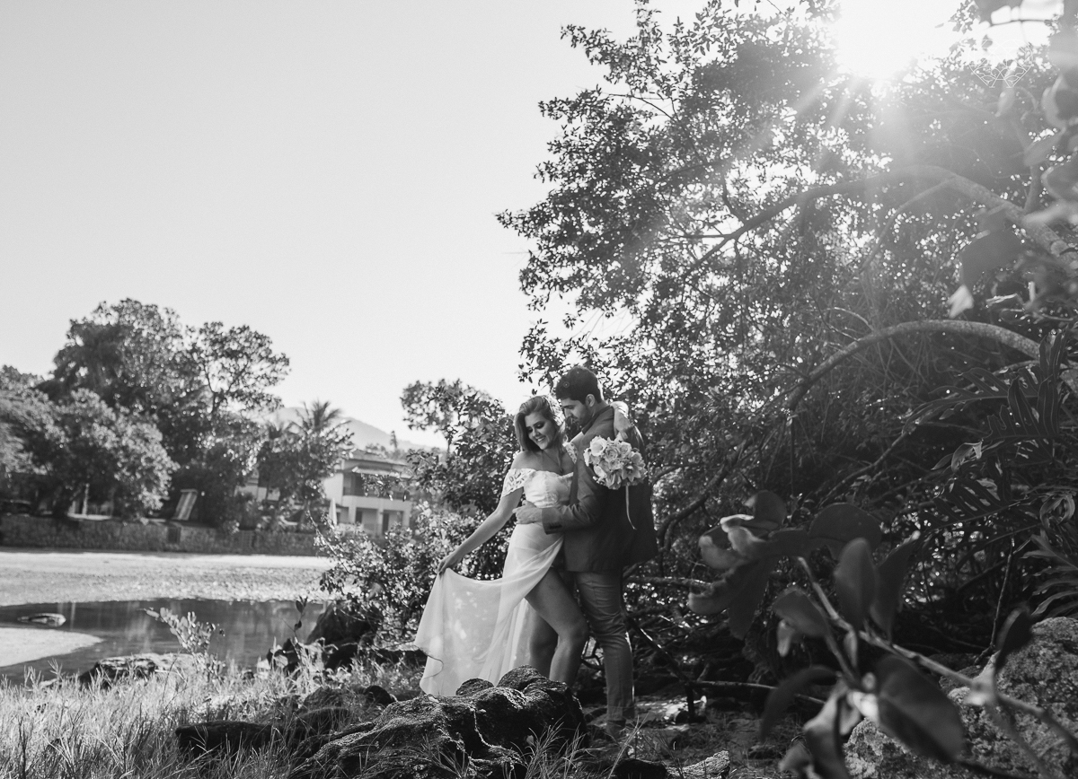 ensaio pre casamento pre wedding na praia das conchas no guaruja noiva de roupa branca e buque e noivo com roupa sociall fotos feitas na agua  na grama e correndo nas pedras ensaio feito pela fotografa premiada nayara andrade de santos