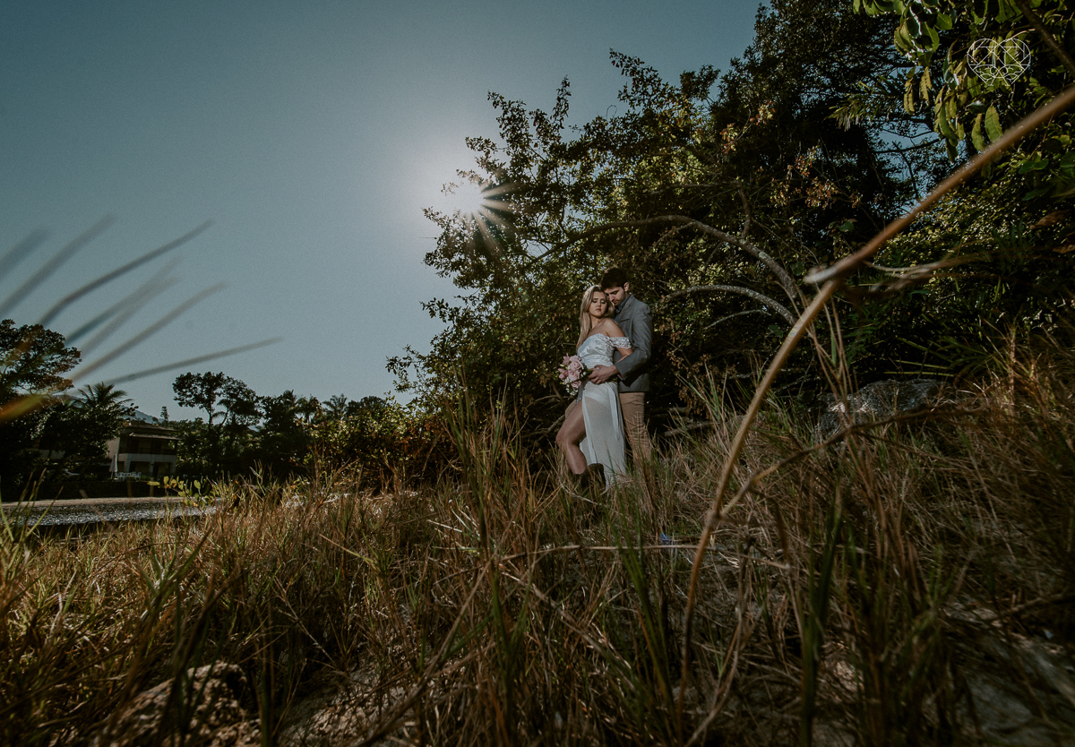 ensaio pre casamento pre wedding na praia das conchas no guaruja noiva de roupa branca e buque e noivo com roupa sociall fotos feitas na agua  na grama e correndo nas pedras ensaio feito pela fotografa premiada nayara andrade de santos