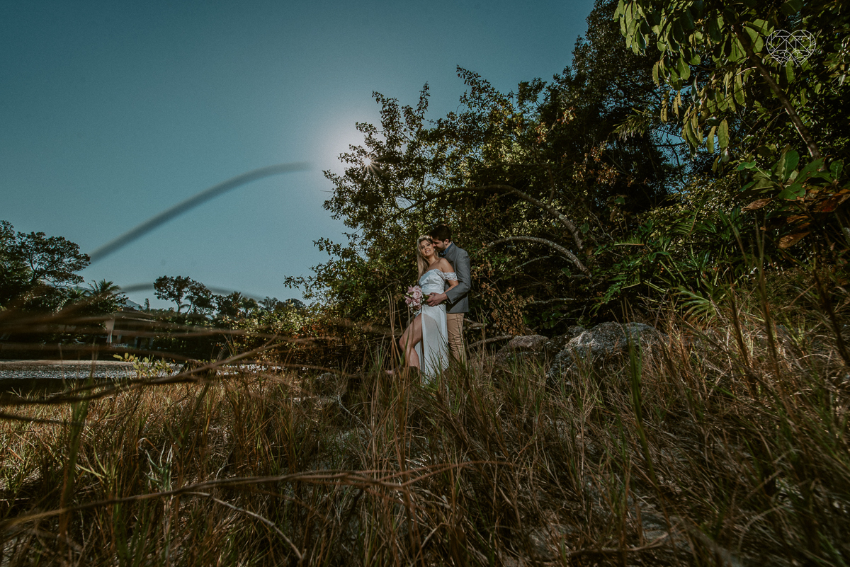ensaio pre casamento pre wedding na praia das conchas no guaruja noiva de roupa branca e buque e noivo com roupa sociall fotos feitas na agua  na grama e correndo nas pedras ensaio feito pela fotografa premiada nayara andrade de santos
