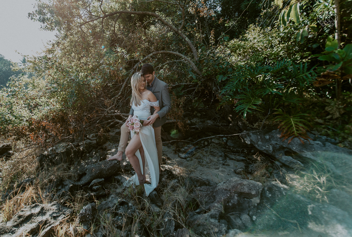 ensaio pre casamento pre wedding na praia das conchas no guaruja noiva de roupa branca e buque e noivo com roupa sociall fotos feitas na agua  na grama e correndo nas pedras ensaio feito pela fotografa premiada nayara andrade de santos