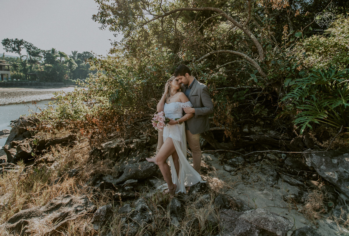 ensaio pre casamento pre wedding na praia das conchas no guaruja noiva de roupa branca e buque e noivo com roupa sociall fotos feitas na agua  na grama e correndo nas pedras ensaio feito pela fotografa premiada nayara andrade de santos