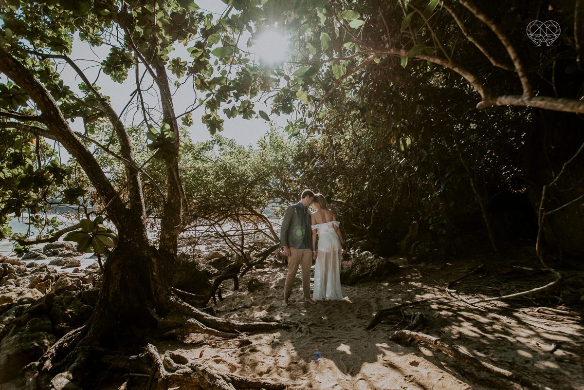 ensaio pre casamento pre wedding na praia das conchas no guaruja noiva de roupa branca e buque e noivo com roupa sociall fotos feitas na agua  na grama e correndo nas pedras ensaio feito pela fotografa premiada nayara andrade de santos