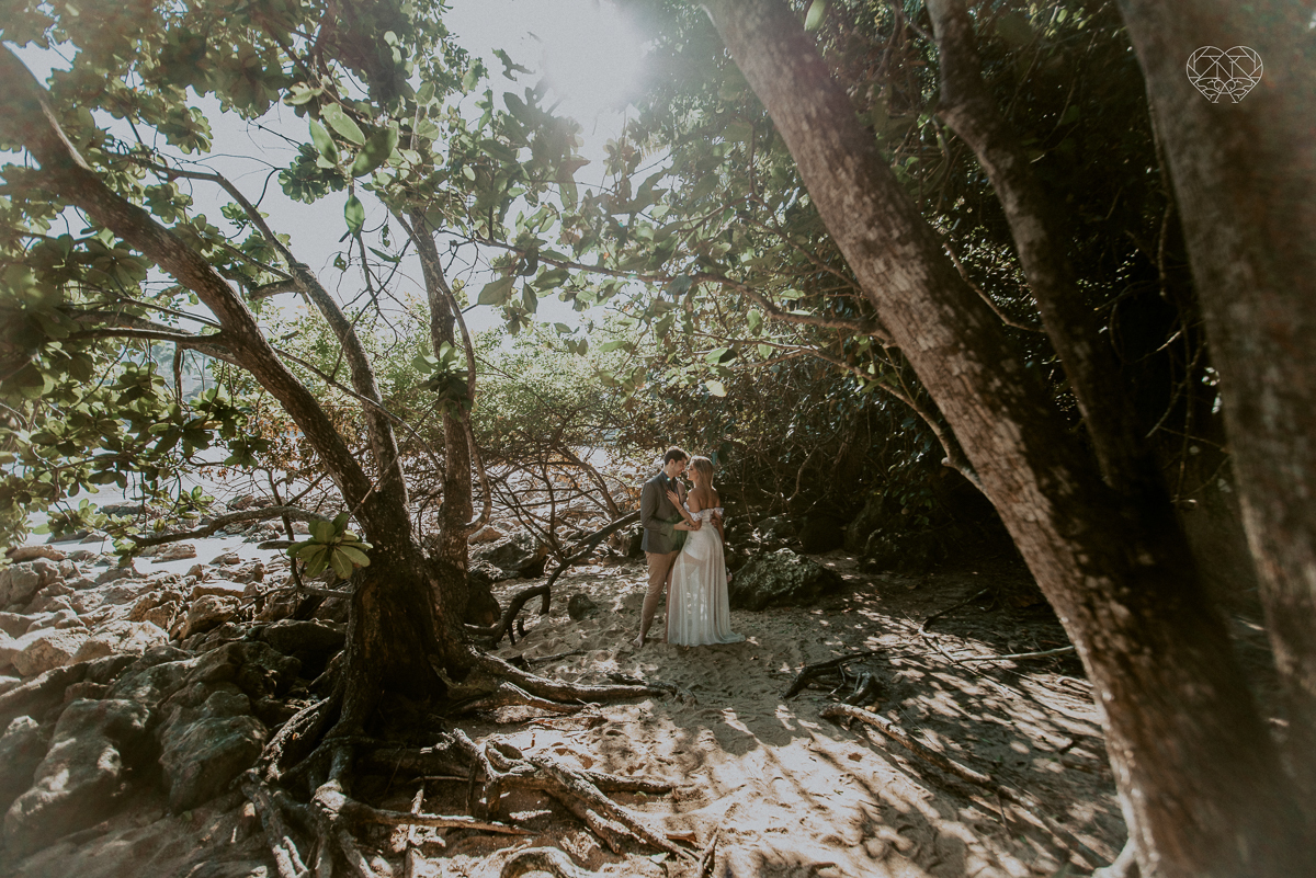 ensaio pre casamento pre wedding na praia das conchas no guaruja noiva de roupa branca e buque e noivo com roupa sociall fotos feitas na agua  na grama e correndo nas pedras ensaio feito pela fotografa premiada nayara andrade de santos
