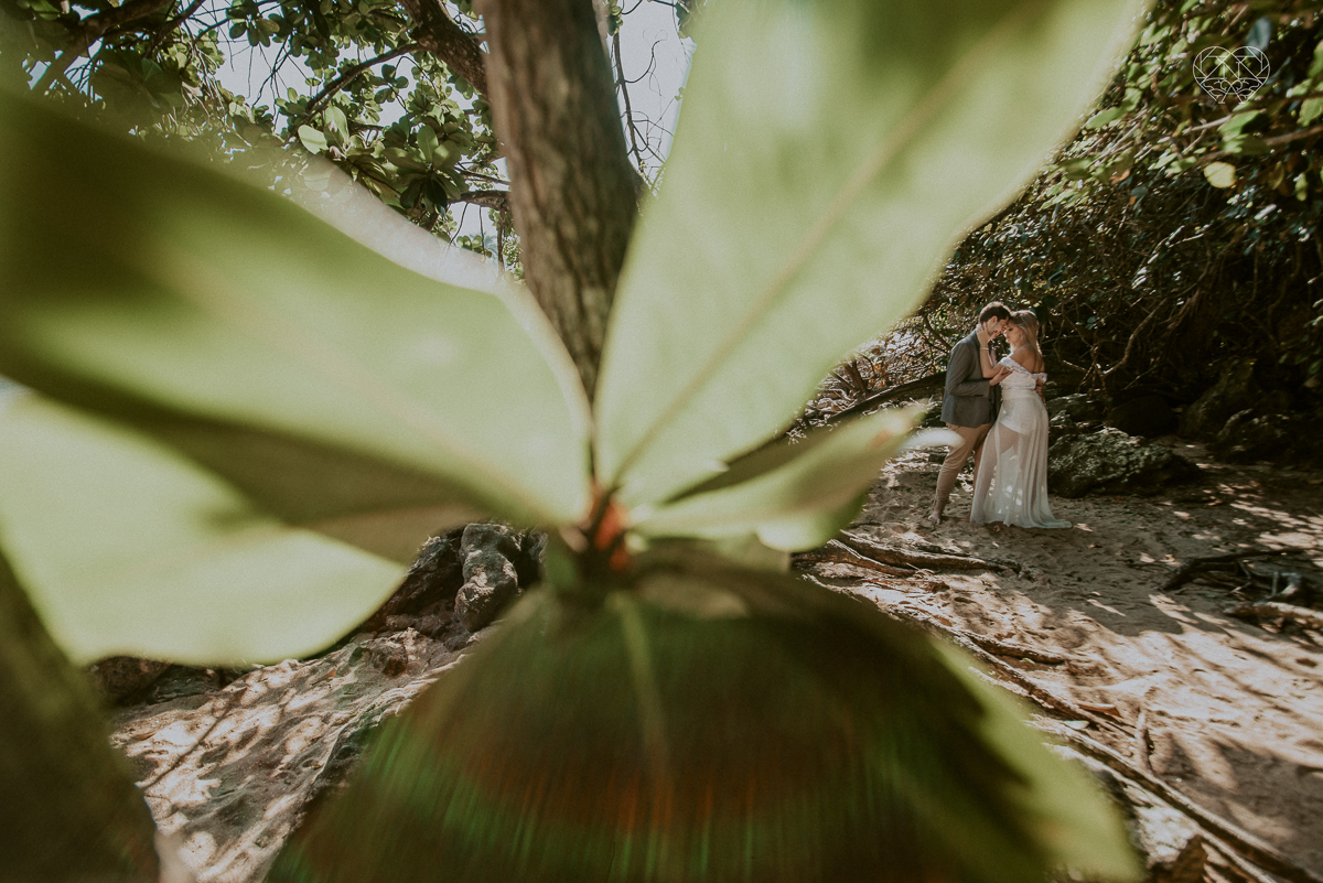 ensaio pre casamento pre wedding na praia das conchas no guaruja noiva de roupa branca e buque e noivo com roupa sociall fotos feitas na agua  na grama e correndo nas pedras ensaio feito pela fotografa premiada nayara andrade de santos