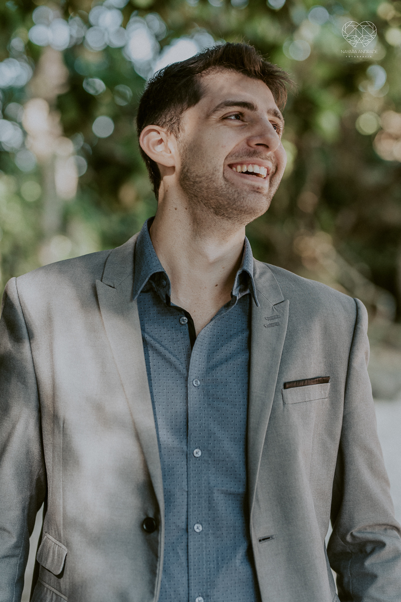 ensaio pre casamento pre wedding na praia das conchas no guaruja noiva de roupa branca e buque e noivo com roupa sociall fotos feitas na agua  na grama e correndo nas pedras ensaio feito pela fotografa premiada nayara andrade de santos
