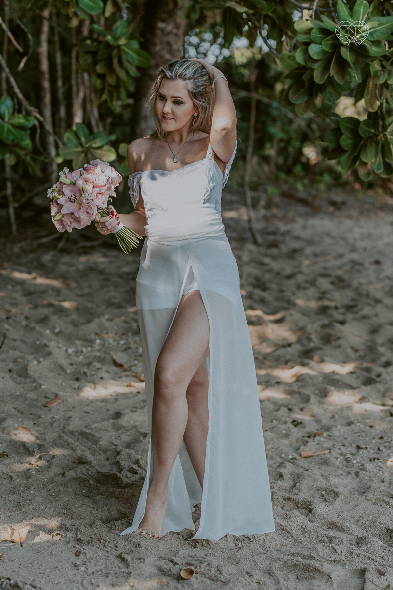 ensaio pre casamento pre wedding na praia das conchas no guaruja noiva de roupa branca e buque e noivo com roupa sociall fotos feitas na agua  na grama e correndo nas pedras ensaio feito pela fotografa premiada nayara andrade de santos