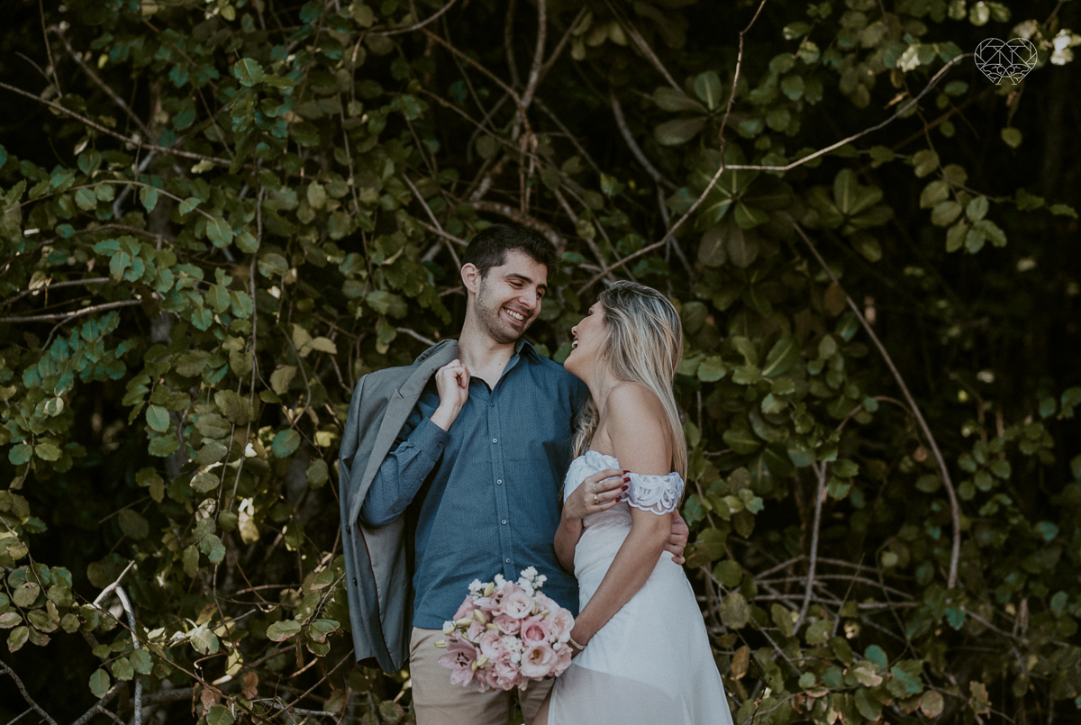 ensaio pre casamento pre wedding na praia das conchas no guaruja noiva de roupa branca e buque e noivo com roupa sociall fotos feitas na agua  na grama e correndo nas pedras ensaio feito pela fotografa premiada nayara andrade de santos