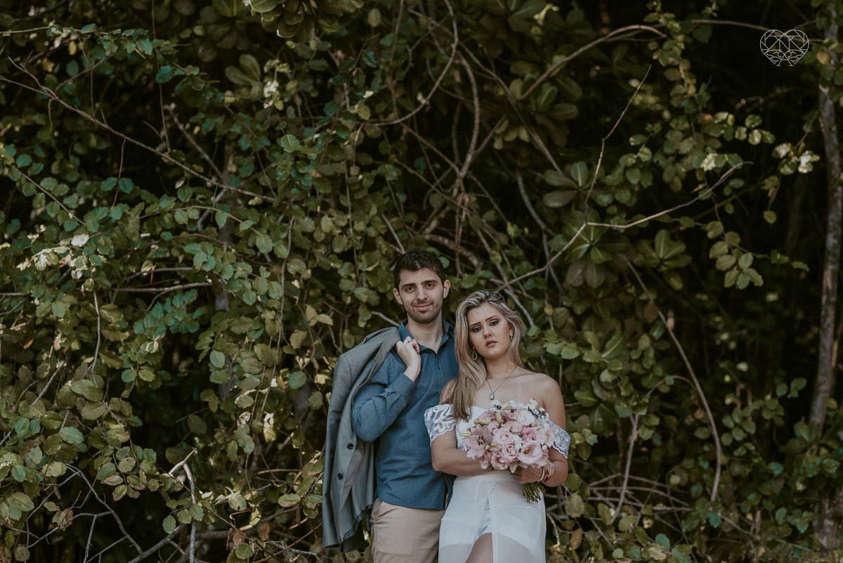 ensaio pre casamento pre wedding na praia das conchas no guaruja noiva de roupa branca e buque e noivo com roupa sociall fotos feitas na agua  na grama e correndo nas pedras ensaio feito pela fotografa premiada nayara andrade de santos