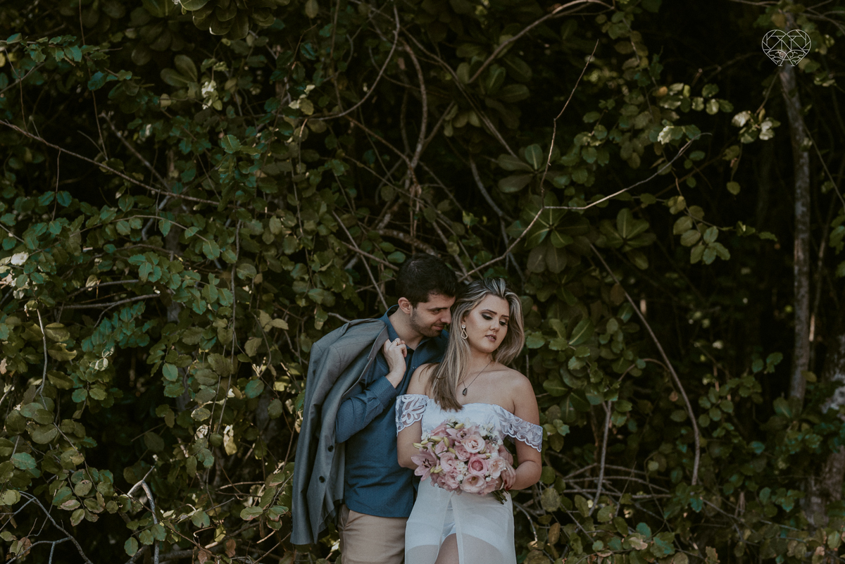 ensaio pre casamento pre wedding na praia das conchas no guaruja noiva de roupa branca e buque e noivo com roupa sociall fotos feitas na agua  na grama e correndo nas pedras ensaio feito pela fotografa premiada nayara andrade de santos