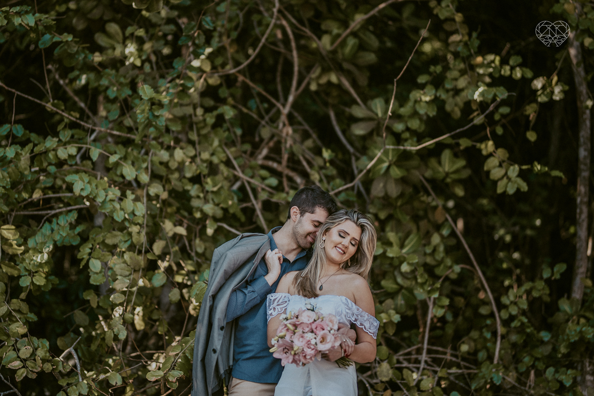 ensaio pre casamento pre wedding na praia das conchas no guaruja noiva de roupa branca e buque e noivo com roupa sociall fotos feitas na agua  na grama e correndo nas pedras ensaio feito pela fotografa premiada nayara andrade de santos