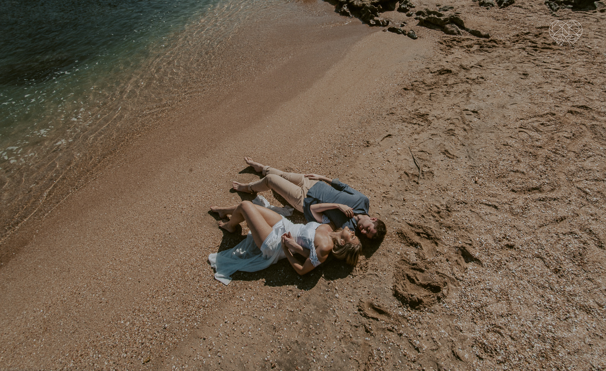 ensaio pre casamento pre wedding na praia das conchas no guaruja noiva de roupa branca e buque e noivo com roupa sociall fotos feitas na agua  na grama e correndo nas pedras ensaio feito pela fotografa premiada nayara andrade de santos