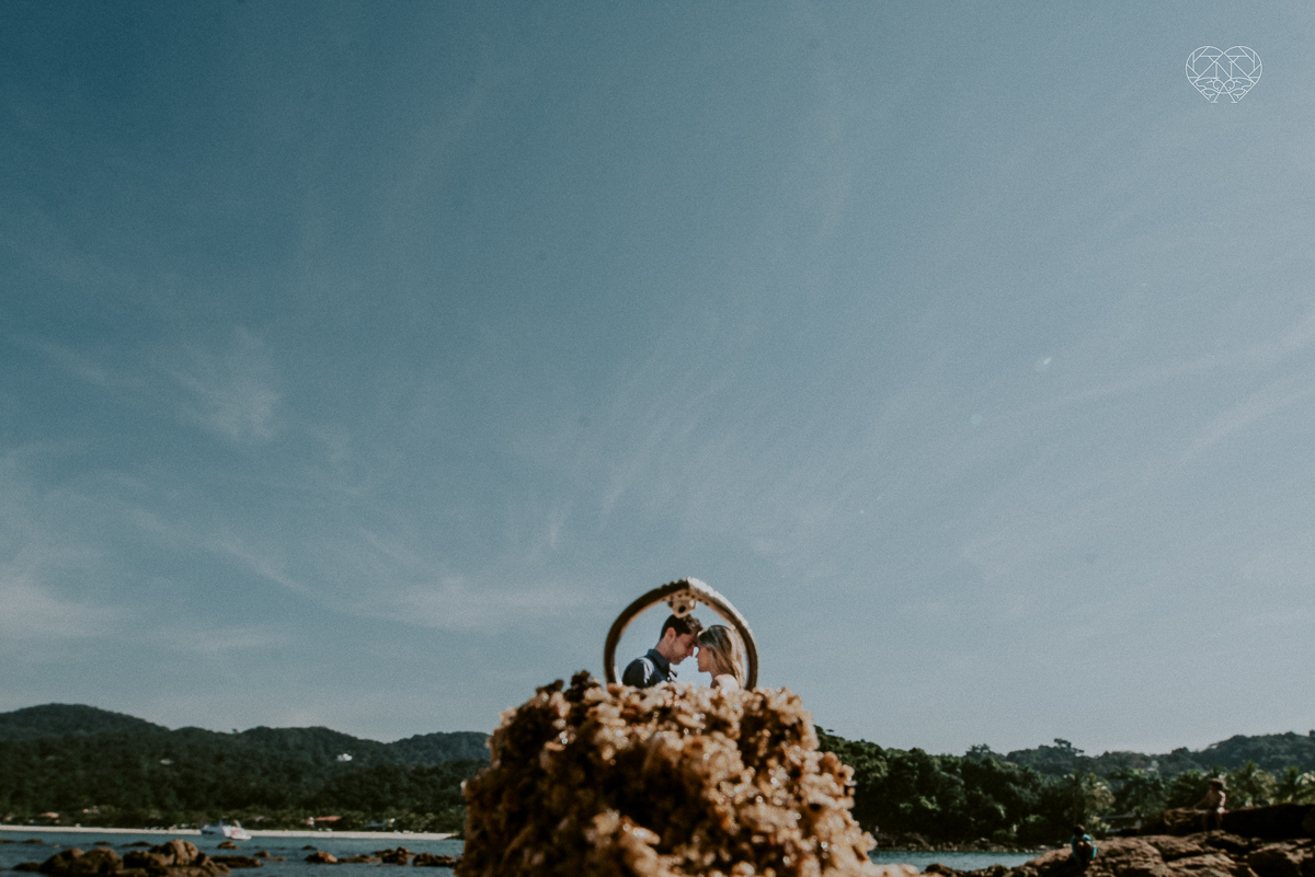 ensaio pre casamento pre wedding na praia das conchas no guaruja noiva de roupa branca e buque e noivo com roupa sociall fotos feitas na agua  na grama e correndo nas pedras ensaio feito pela fotografa premiada nayara andrade de santos
