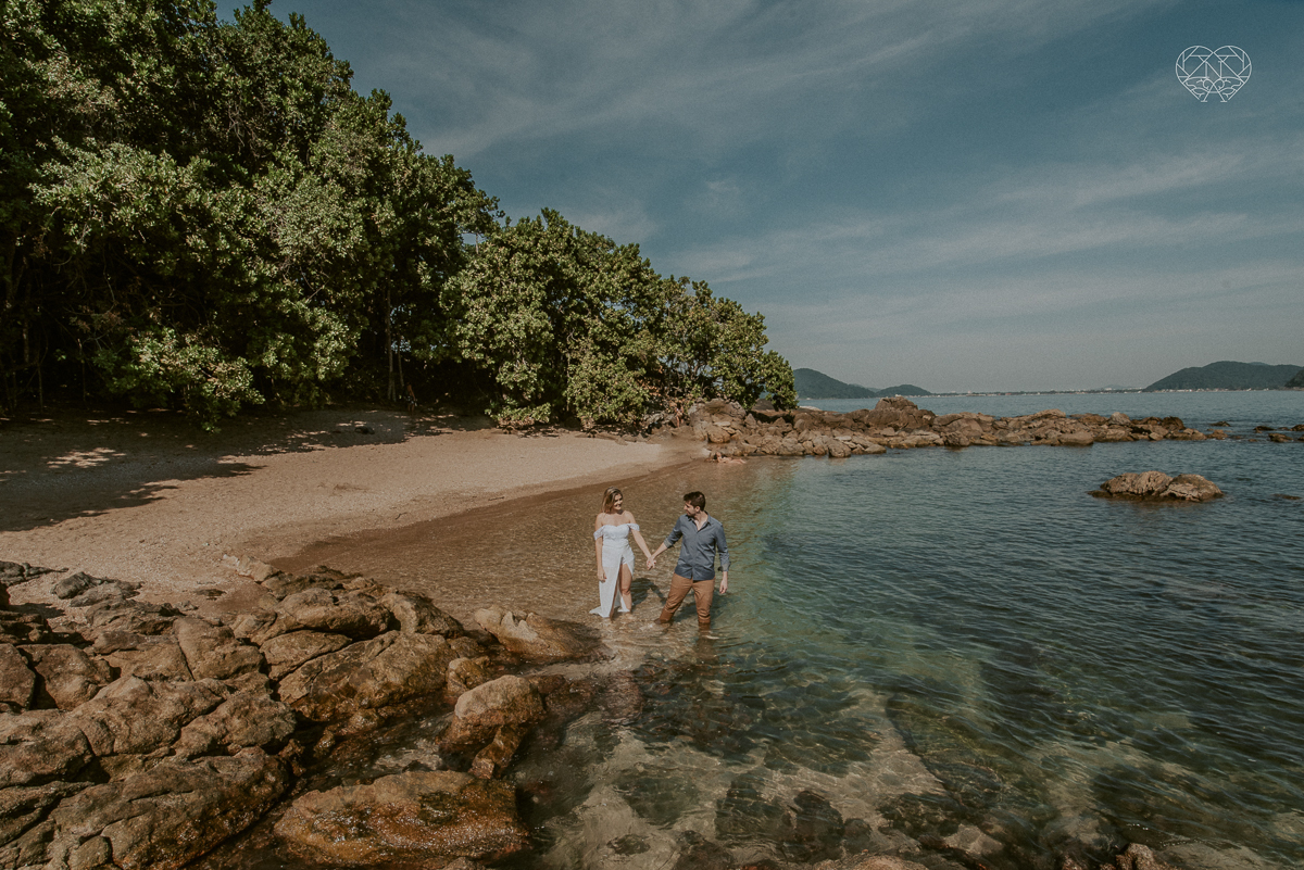 ensaio pre casamento pre wedding na praia das conchas no guaruja noiva de roupa branca e buque e noivo com roupa sociall fotos feitas na agua  na grama e correndo nas pedras ensaio feito pela fotografa premiada nayara andrade de santos