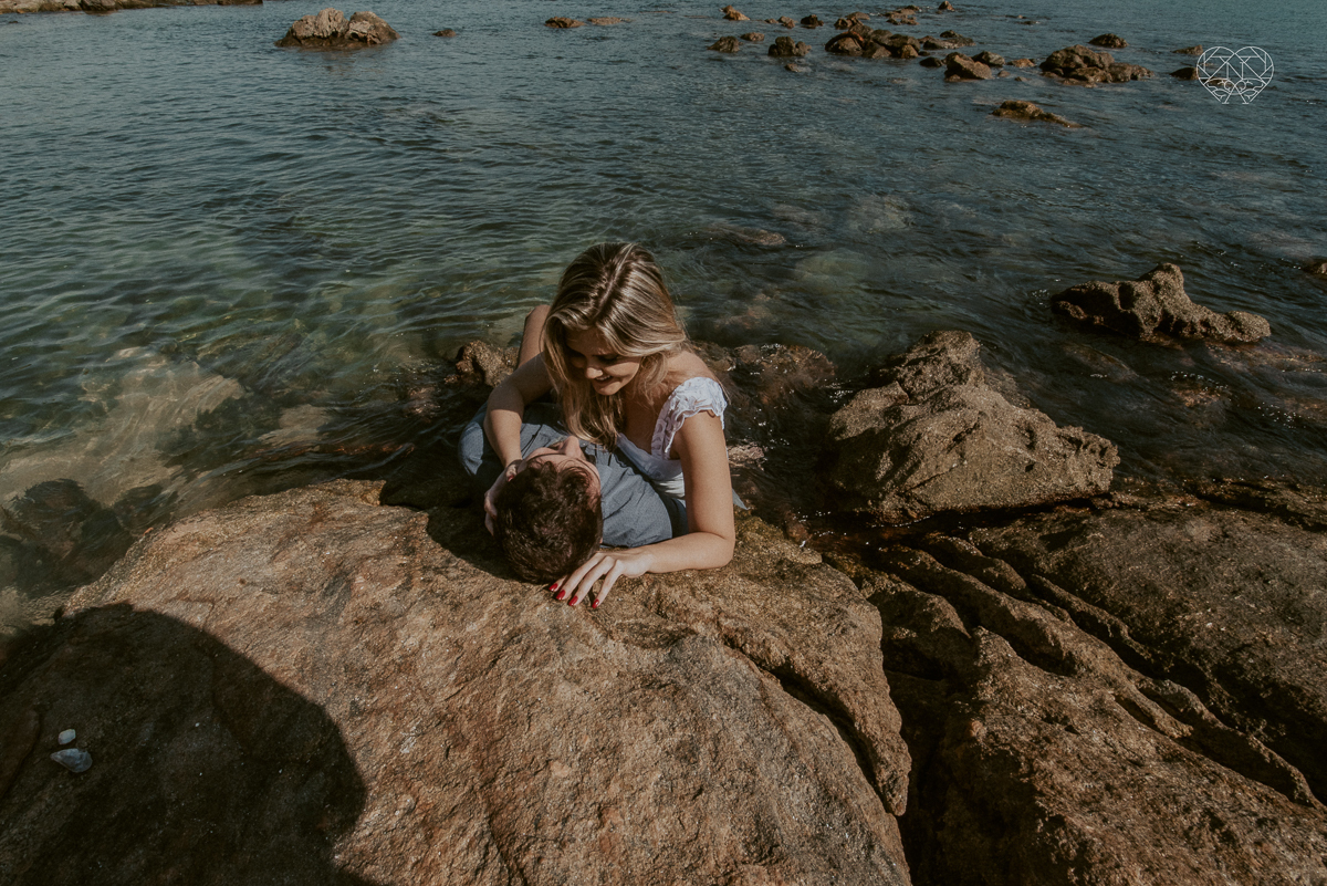 ensaio pre casamento pre wedding na praia das conchas no guaruja noiva de roupa branca e buque e noivo com roupa sociall fotos feitas na agua  na grama e correndo nas pedras ensaio feito pela fotografa premiada nayara andrade de santos