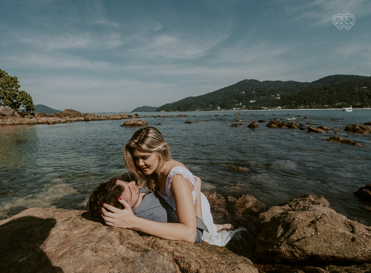 ensaio pre casamento pre wedding na praia das conchas no guaruja noiva de roupa branca e buque e noivo com roupa sociall fotos feitas na agua  na grama e correndo nas pedras ensaio feito pela fotografa premiada nayara andrade de santos