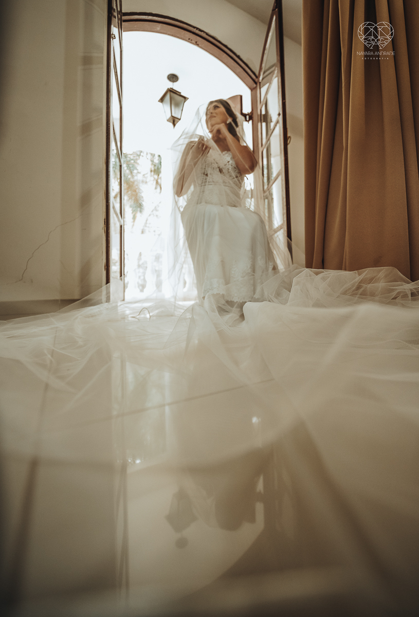casamento de dia no ravena garden ao ar livre noivo com roupa branca noiva com mantilha fotos pela fotografa premiada nayara andrade de santos casamento com passarela espelhada