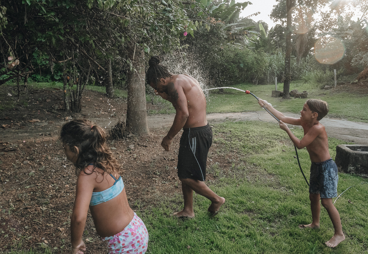 ensaio familia lifestyle brincando de mangueira no quintal de casa com o papai crianças e o cachorro fotografado pela fotografa premiada nayara andrade nayara andrade fotografia