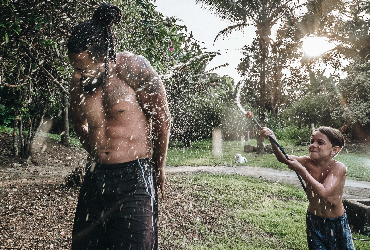 ensaio familia lifestyle brincando de mangueira no quintal de casa com o papai crianças e o cachorro fotografado pela fotografa premiada nayara andrade nayara andrade fotografia