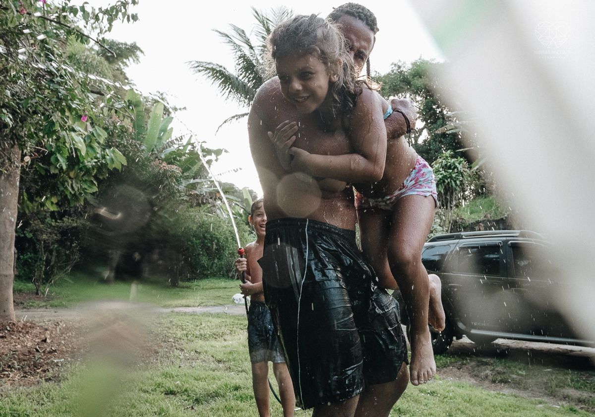 ensaio familia lifestyle brincando de mangueira no quintal de casa com o papai crianças e o cachorro fotografado pela fotografa premiada nayara andrade nayara andrade fotografia
