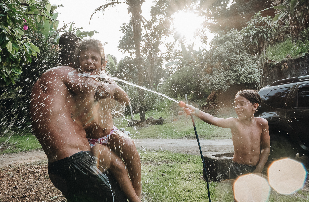 ensaio familia lifestyle brincando de mangueira no quintal de casa com o papai crianças e o cachorro fotografado pela fotografa premiada nayara andrade nayara andrade fotografia