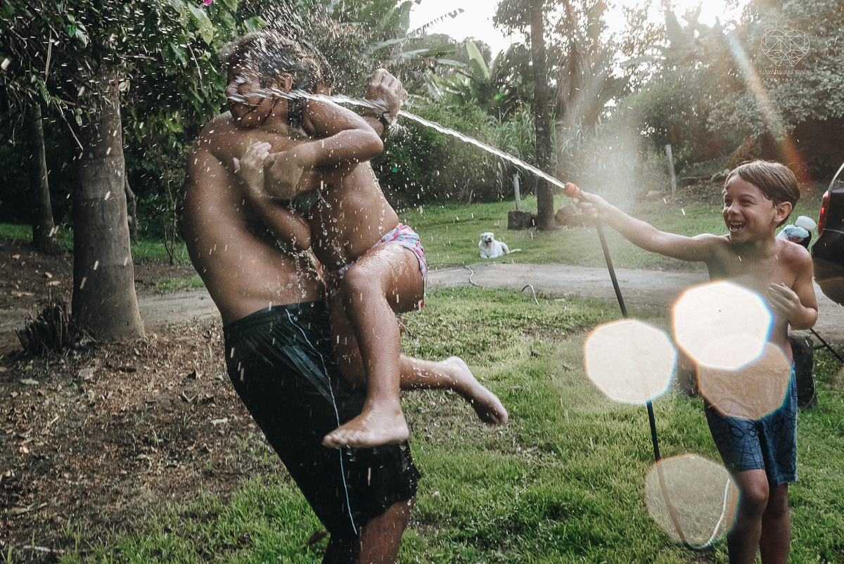 ensaio familia lifestyle brincando de mangueira no quintal de casa com o papai crianças e o cachorro fotografado pela fotografa premiada nayara andrade nayara andrade fotografia