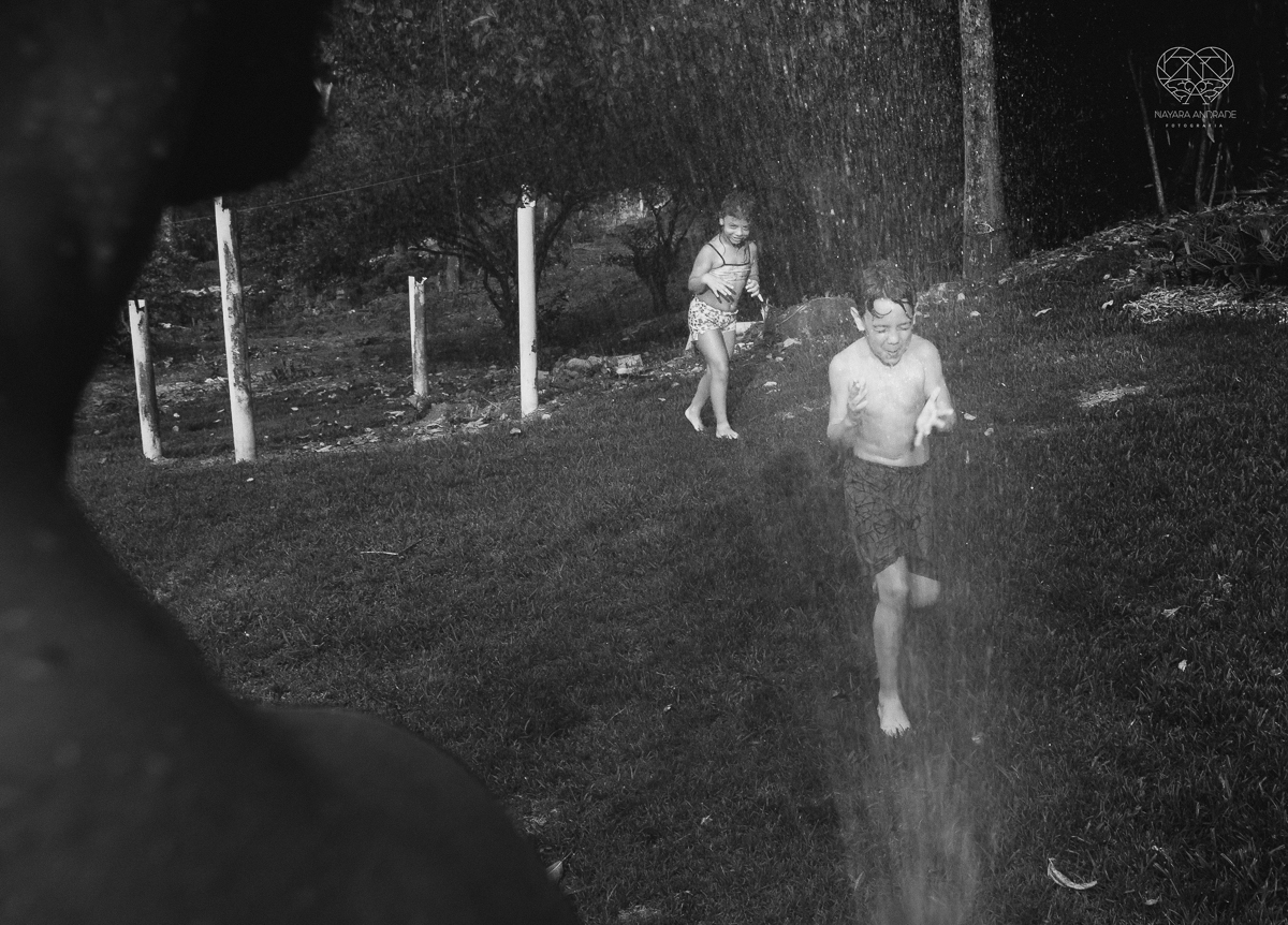 ensaio familia lifestyle brincando de mangueira no quintal de casa com o papai crianças e o cachorro fotografado pela fotografa premiada nayara andrade nayara andrade fotografia