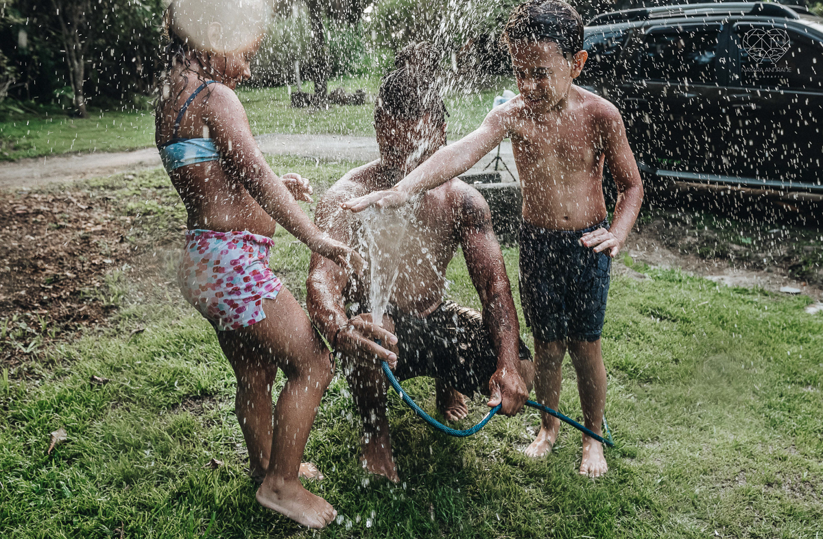 ensaio familia lifestyle brincando de mangueira no quintal de casa com o papai crianças e o cachorro fotografado pela fotografa premiada nayara andrade nayara andrade fotografia