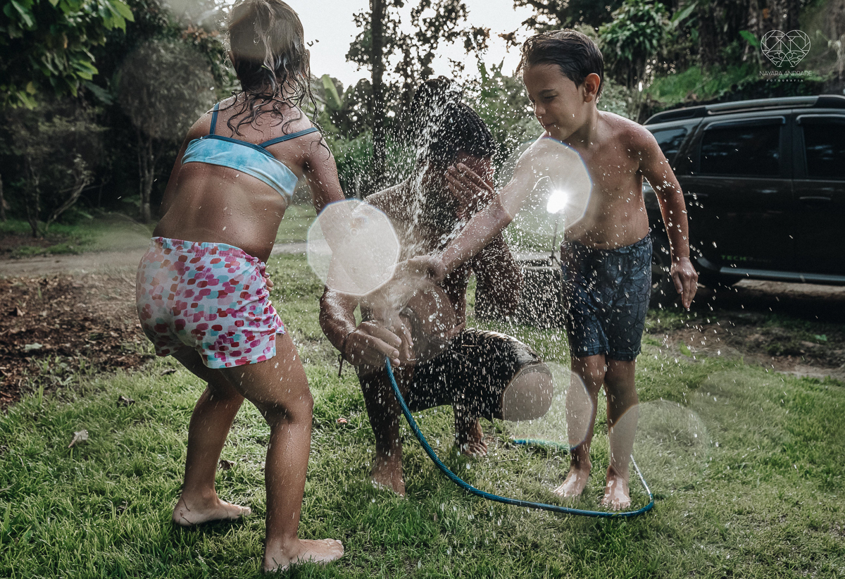 ensaio familia lifestyle brincando de mangueira no quintal de casa com o papai crianças e o cachorro fotografado pela fotografa premiada nayara andrade nayara andrade fotografia