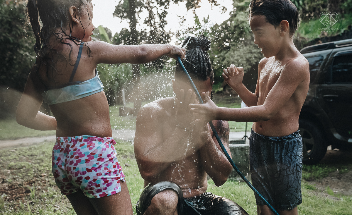 ensaio familia lifestyle brincando de mangueira no quintal de casa com o papai crianças e o cachorro fotografado pela fotografa premiada nayara andrade nayara andrade fotografia