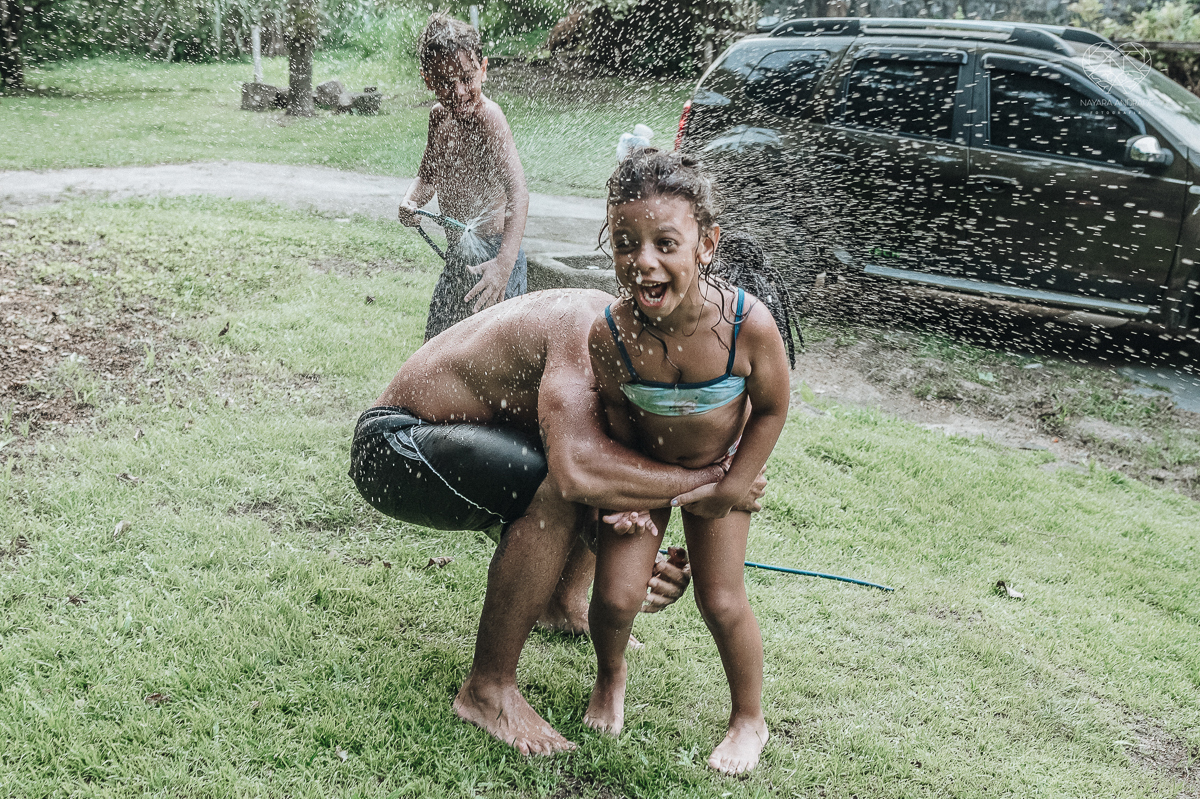 ensaio familia lifestyle brincando de mangueira no quintal de casa com o papai crianças e o cachorro fotografado pela fotografa premiada nayara andrade nayara andrade fotografia