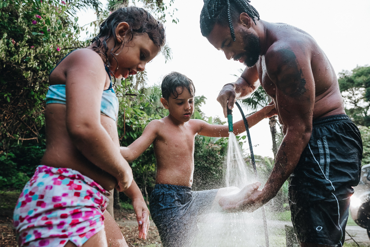 ensaio familia lifestyle brincando de mangueira no quintal de casa com o papai crianças e o cachorro fotografado pela fotografa premiada nayara andrade nayara andrade fotografia