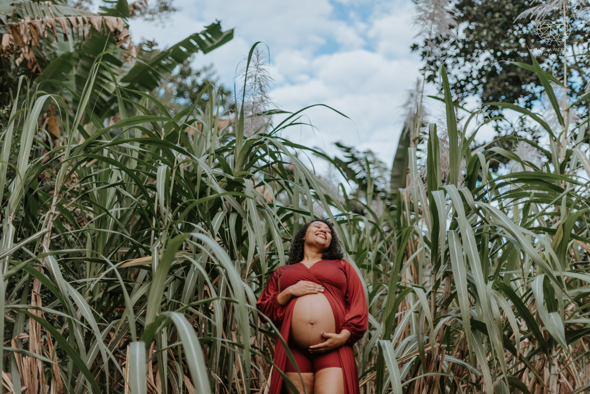 ensaio gestante ao ar livre com vestido longo  no verde arvore campo e gramas feito pela fotografa premiada nayara andrade fotografia de santos litoral de sao paulo
