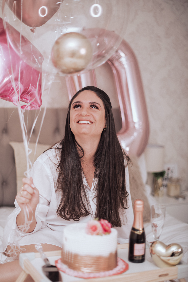 Fotos de mulher comemorando o aniversario no quarto. Ensaio feminino com balão bolo de aniversario tons de rosa e rosado ensaio feito em casa na pandemia pela fotografa premiada nayara andrade em santos guaruja 