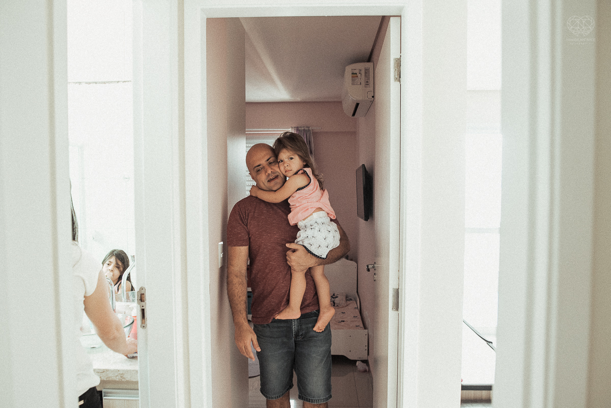 Fotografia de familia fotos feitas em casa ao natural da familia mae pai e duas filhas com pijama acordando brincando no predio. fotos feitas pela fotografa premiada nayara andrade de santos litoral de sao paulo