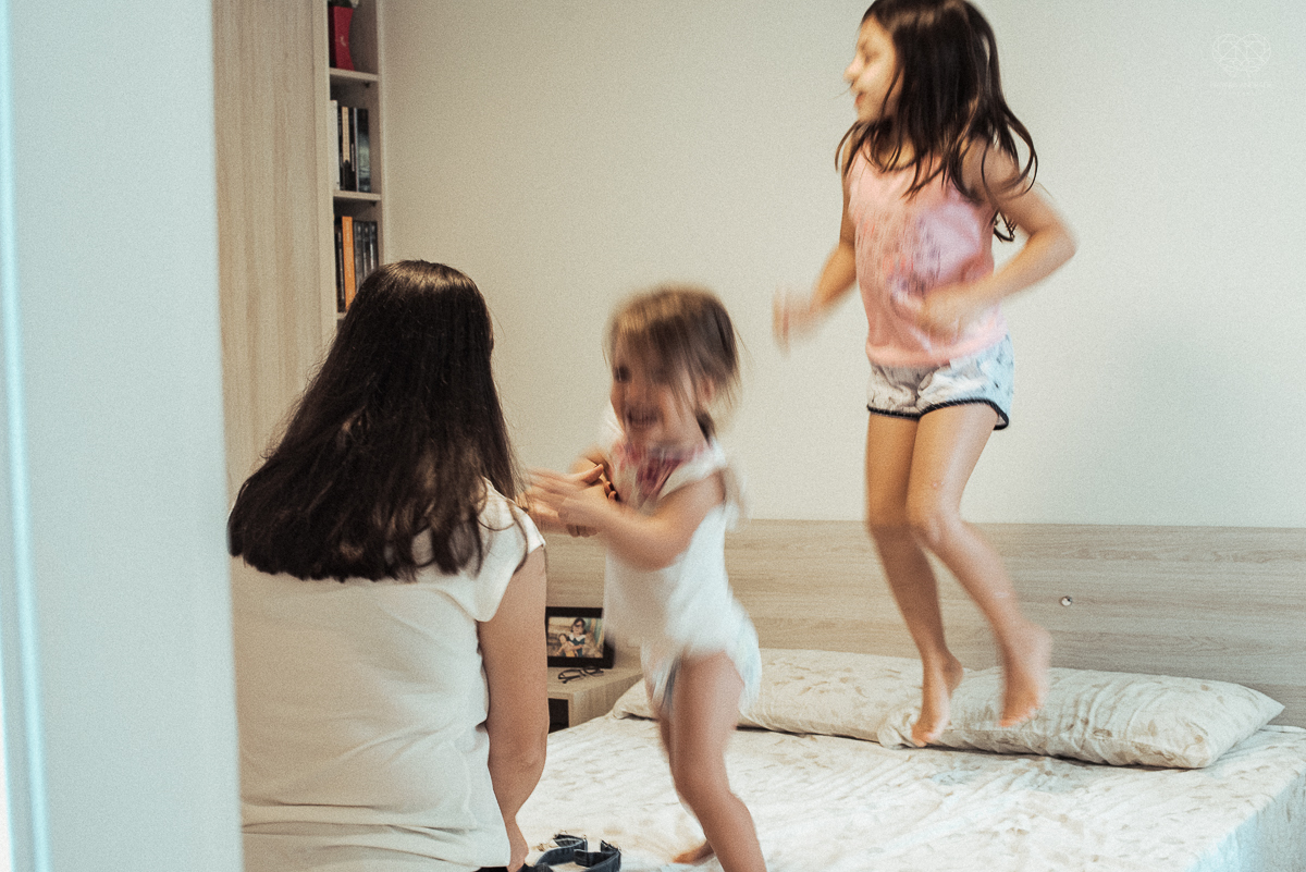 Fotografia de familia fotos feitas em casa ao natural da familia mae pai e duas filhas com pijama acordando brincando no predio. fotos feitas pela fotografa premiada nayara andrade de santos litoral de sao paulo