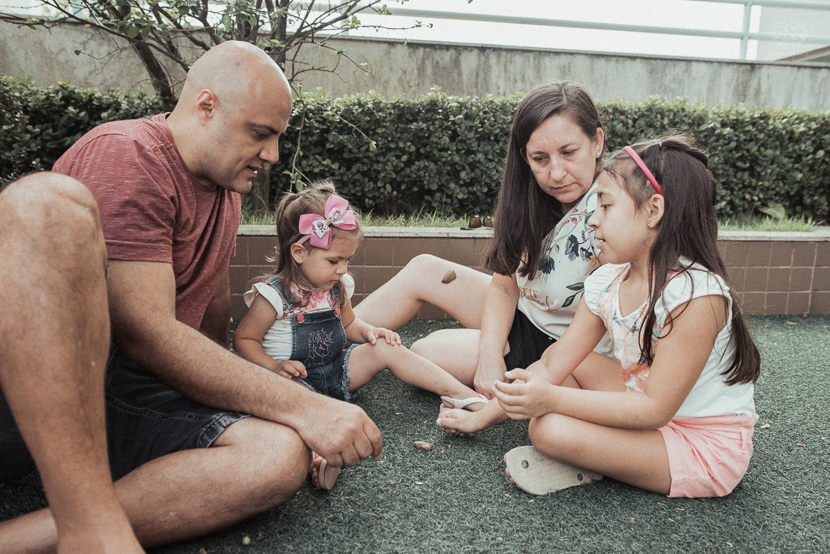 Fotografia de familia fotos feitas em casa ao natural da familia mae pai e duas filhas com pijama acordando brincando no predio. fotos feitas pela fotografa premiada nayara andrade de santos litoral de sao paulo
