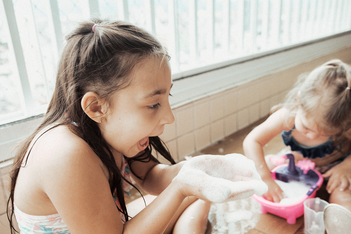 Fotografia de familia fotos feitas em casa ao natural da familia mae pai e duas filhas com pijama acordando brincando no predio. fotos feitas pela fotografa premiada nayara andrade de santos litoral de sao paulo