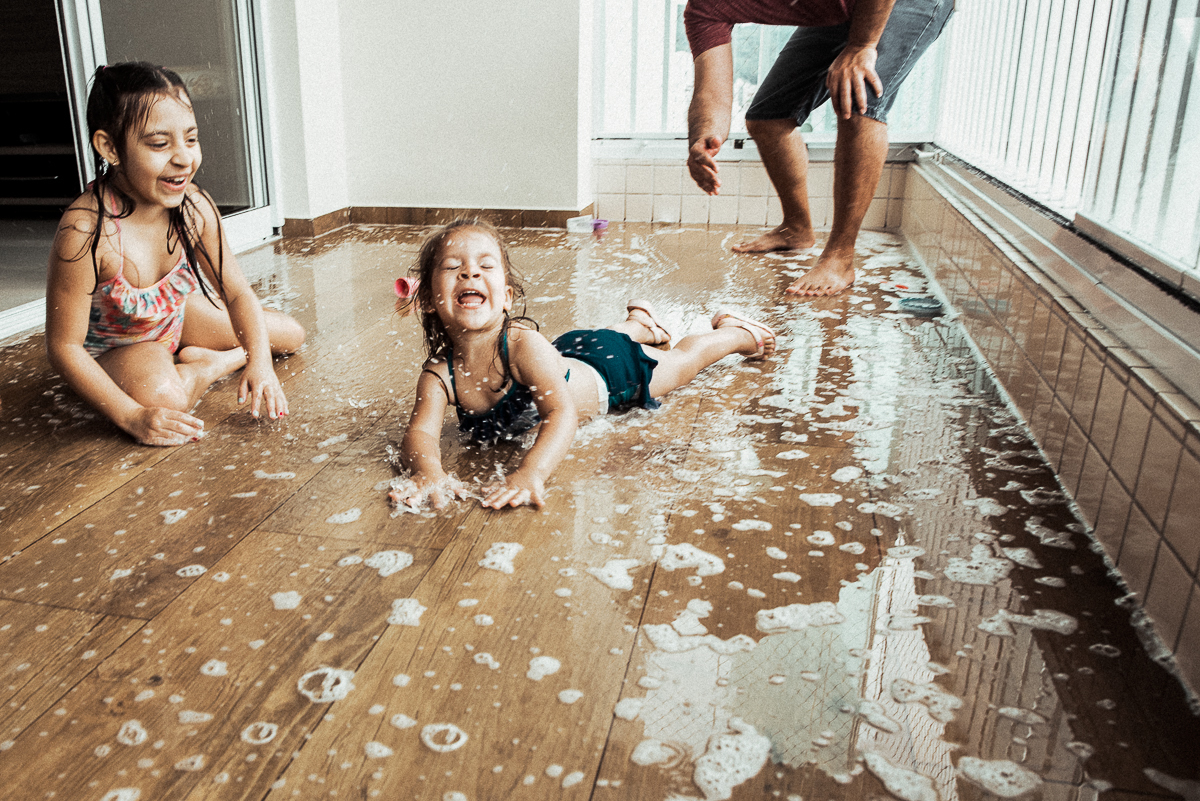 Fotografia de familia fotos feitas em casa ao natural da familia mae pai e duas filhas com pijama acordando brincando no predio. fotos feitas pela fotografa premiada nayara andrade de santos litoral de sao paulo