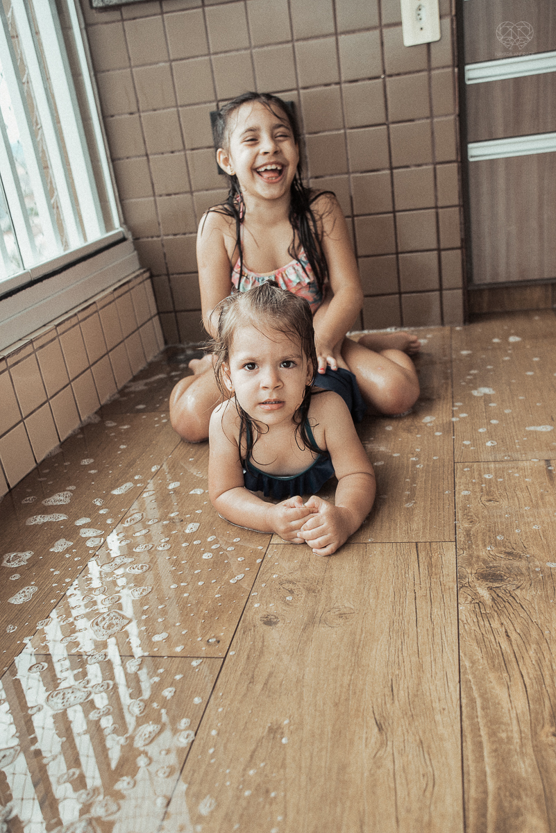 Fotografia de familia fotos feitas em casa ao natural da familia mae pai e duas filhas com pijama acordando brincando no predio. fotos feitas pela fotografa premiada nayara andrade de santos litoral de sao paulo